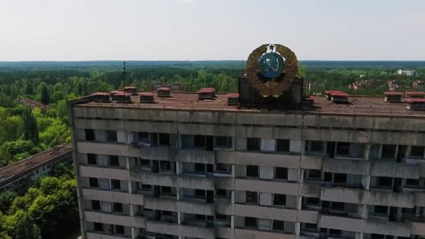 Verlaten multi tellend hoofdgebouw met in de Sovjet-Unie wapenschild op de gevel in de dode stad Pripyat. Ghost town in de zone van Chernobyl. - Video