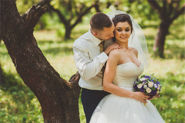 Bruid en bruidegom in een park kissing.couple jonggehuwden bij huwelijk in natuur groene woud zijn foto portret. - Foto, afbeelding