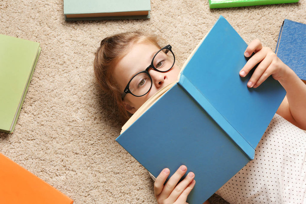 Cute girl with books lying on floor - Foto, afbeelding