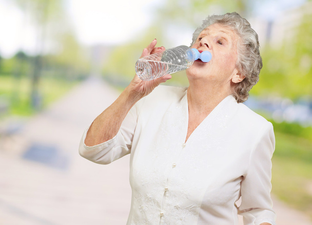 Madura sedienta mujer bebiendo agua
 - Foto, imagen
