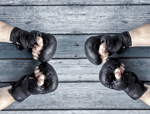 Two pairs of human hands in black leather boxing gloves facing e - Photo, Image