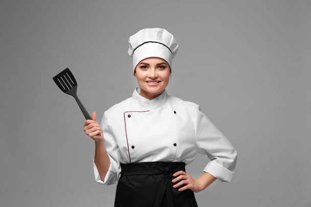 Portrait of young woman chef with spatula on light background - Photo, Image