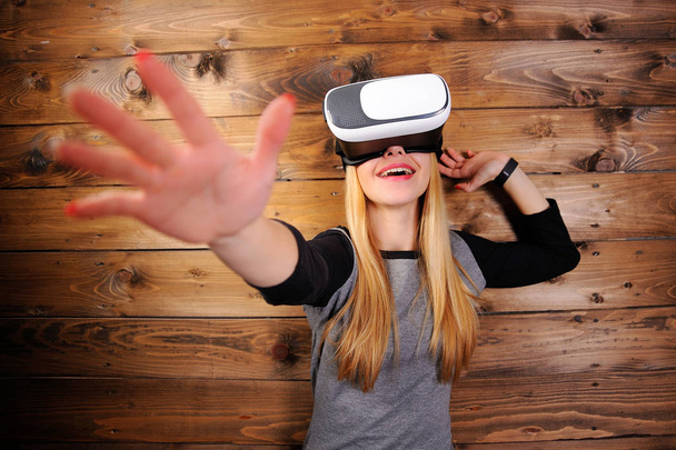 Chica joven con gafas de realidad virtual en el backgro de madera
 - Foto, Imagen
