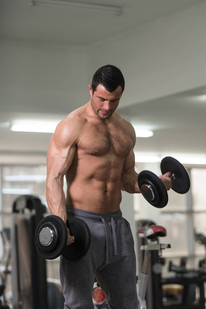 Biceps Exercise With Dumbbell in a Fitness Center - Foto, immagini