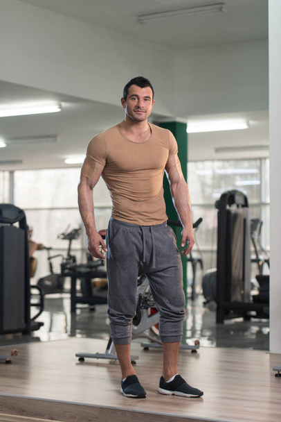 Strong Man in Brown T-shirt Background Gym - Foto, imagen
