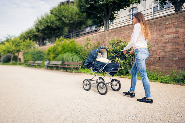 Young Mother With Baby Stroller In The Park - 写真・画像