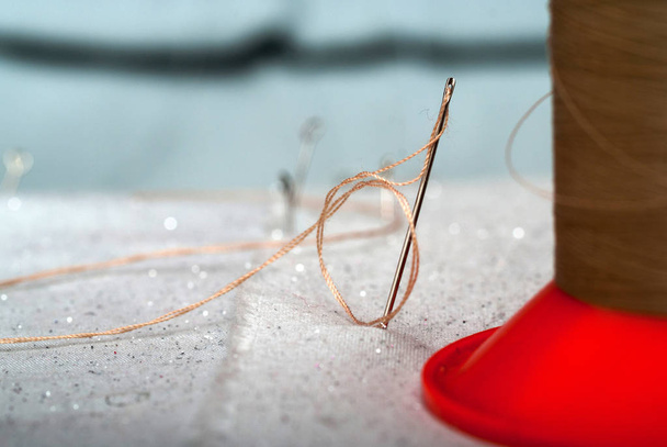 Detalhe de uma agulha com fio no alfaiate da sala de trabalho
 - Foto, Imagem