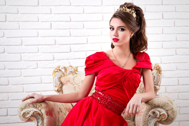 Elegant woman in a long red dress sitting on a chair - Φωτογραφία, εικόνα