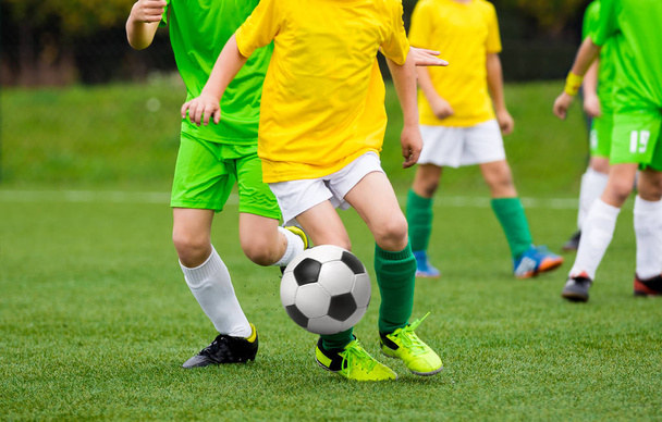 Τρέχοντας ποδοσφαιριστές ποδόσφαιρο με την μπάλα. Ποδοσφαιριστές κλοτσιές Ποδοσφαιρικό αγώνα στο γήπεδο. Νέοι έφηβος ποδόσφαιρο παιχνίδι. Νεολαίας αθλητισμού φόντο - Φωτογραφία, εικόνα