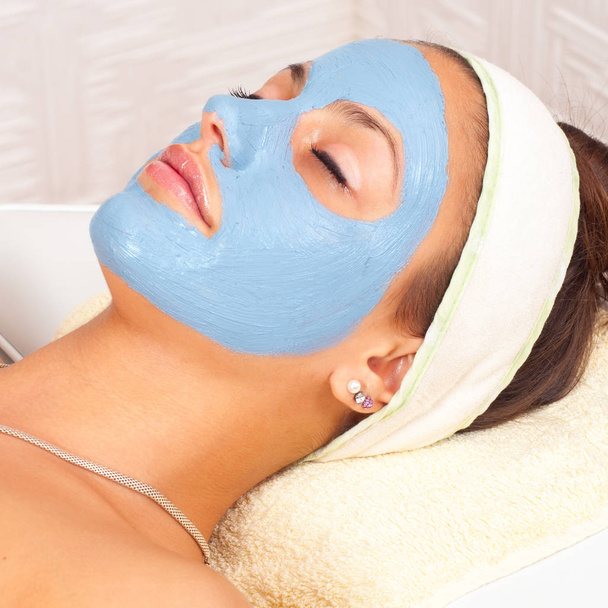 Meisje met gezichtsmasker en gesloten ogen liggen in de moderne beauty spa - Foto, afbeelding