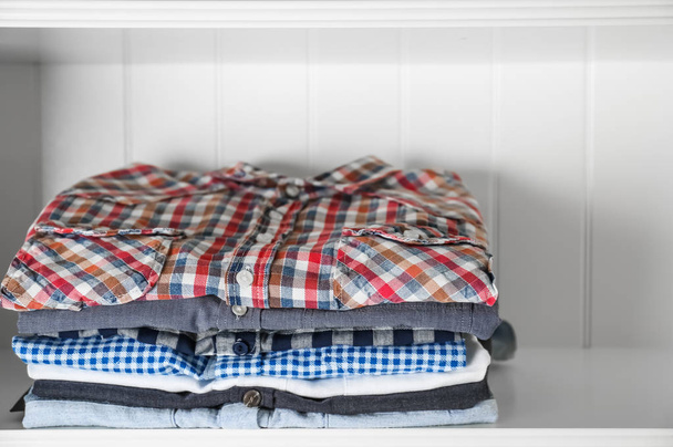 Stack of clothes on shelves - 写真・画像