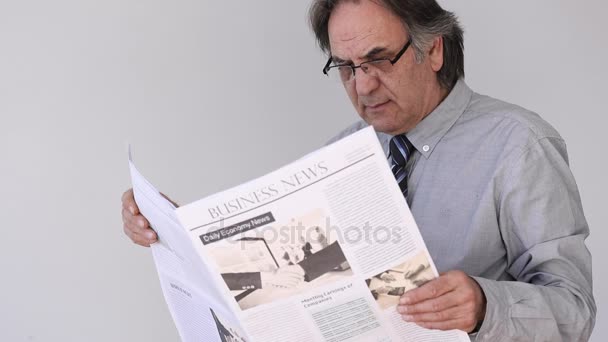Vanhempi mies lukemassa sanomalehteä harmaalla taustalla
 - Materiaali, video