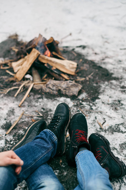 Guy and girl warm feet near a fire - Foto, imagen