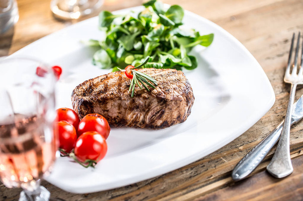 Beef Steak. Juicy beef steak. Gourmet steak with vegetables and glass of rose wine on wooden table - Foto, afbeelding