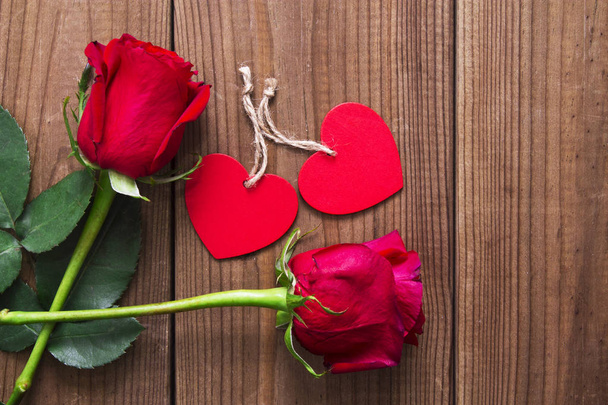Label and red roses on wooden background - Foto, afbeelding