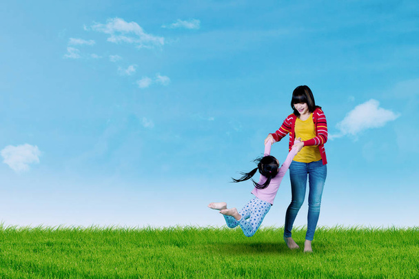 Young mother swings her daughter on meadow  - Photo, Image
