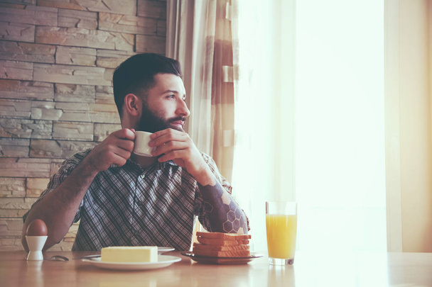 bearded man sitting at table with breakfast  - Foto, imagen