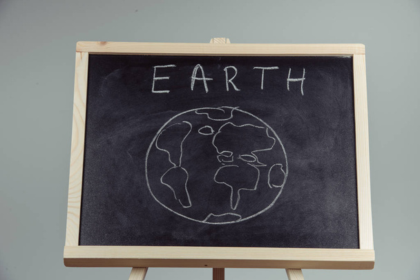 earth written on blackboard with earth symbol, background, high resolution - Photo, image