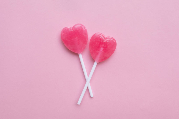 einzelner rosa Valentinstag Herzform Bonbons auf leerem pastellrosa Papier Hintergrund. Liebe. Ansicht von oben. Minimalismus bunten Hipster-Stil. - Foto, Bild