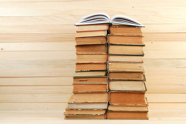 Open boek, stapel hardback boeken op houten tafel. - Foto, afbeelding