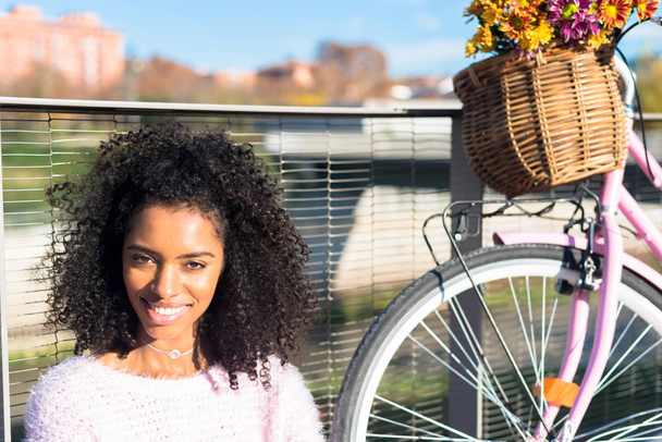 Черная молодая женщина, сидящая у реки на винтажном велосипеде
 - Фото, изображение