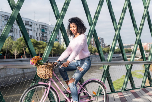 Black young woman riding a vintage bicycle - Фото, изображение