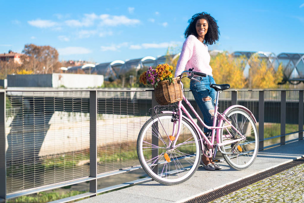 Black young woman riding a vintage bicycle - Photo, image