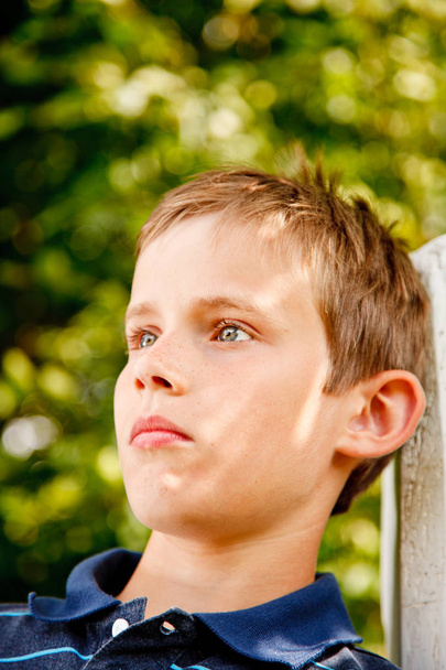 Egy fiatal fiú ül a kertben portréja - Fotó, kép