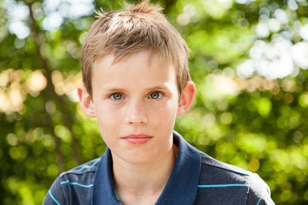 Portret van een jonge jongen zitten in de tuin - Foto, afbeelding