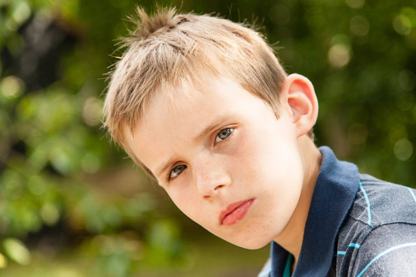 Portrait of a young boy sitting in the garden - Foto, imagen