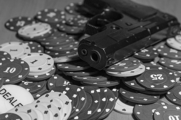 Пистолеты и фишки для покера в черном и белом цветах на игровом столе
 - Фото, изображение