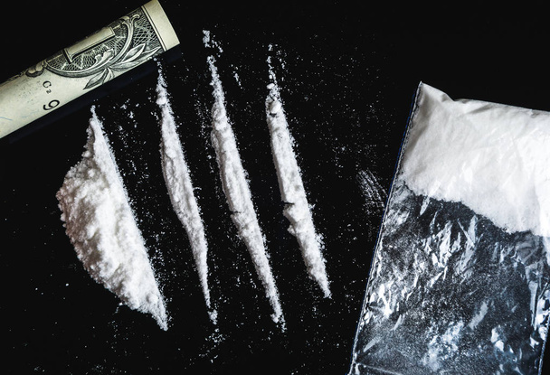 Кокаїнова наркоманія. Лінії кокаїну і банкнота в один долар на чорному
  - Фото, зображення