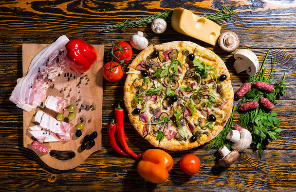 High angle view of pizza on wooden table surrounded by vegetable - Fotoğraf, Görsel