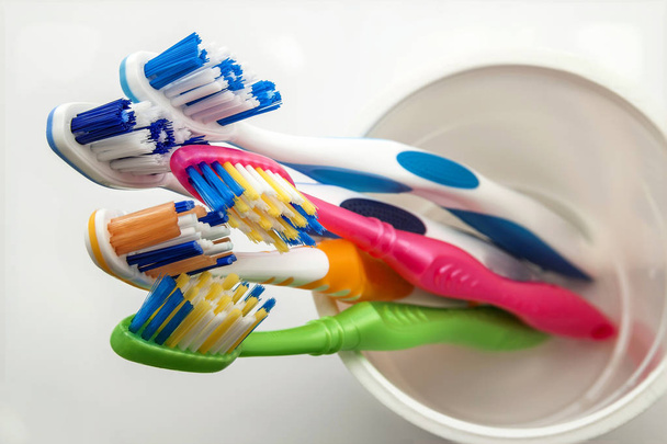 Крупним планом знімок набору різнокольорових зубних щіток у склі на тканині
 - Фото, зображення