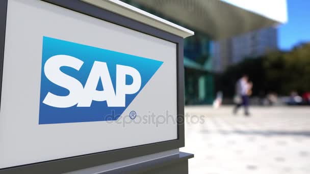 Street signage board with SAP SE logo. Blurred office center and walking people background. Editorial 3D rendering 4K - Metraje, vídeo