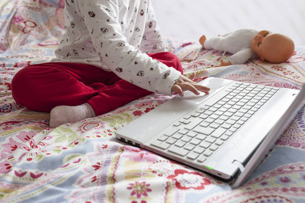 Μικρό κορίτσι να κάθεται στο κρεβάτι και το surfing στο διαδίκτυο στο ρομάντζο του - Φωτογραφία, εικόνα