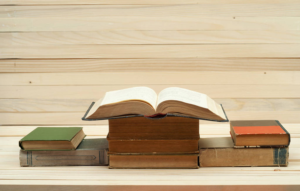 Halom könyvet. Nyitott könyv, keménykötésű könyv, a fából készült asztal. Fontos a tudás. Másolja a hely. Szemközti nézet - Fotó, kép