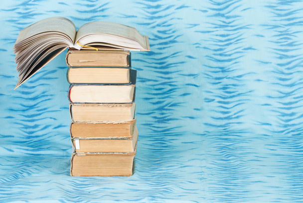 Libro abierto, pila de libros de tapa dura sobre tela azul
 - Foto, Imagen