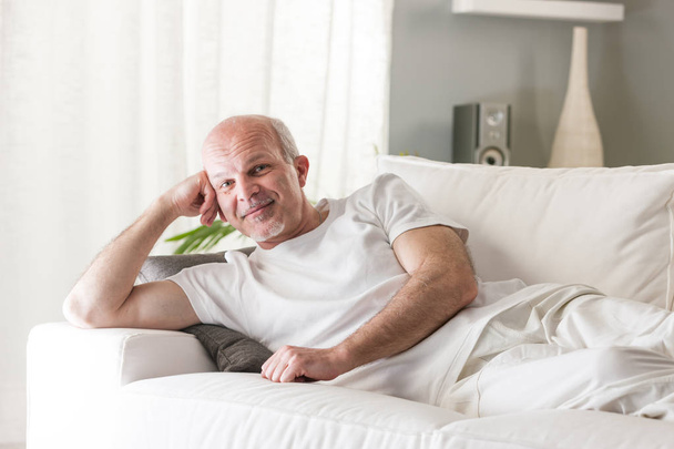 starszy człowiek uśmiechający się zadowolony na kanapie - Zdjęcie, obraz