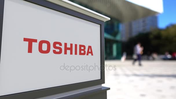 Street signage board with Toshiba Corporation logo. Blurred office center and walking people background. Editorial 3D rendering 4K - Video, Çekim