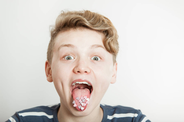 Мальчик, торчащий языком с конфетами в форме сердца
 - Фото, изображение