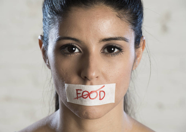 close up rosto de jovem bela mulher latina triste com a boca selada em fita adesiva com o texto sem comida
 - Foto, Imagem