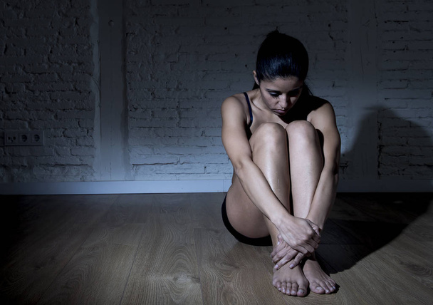 jovem bela mulher latina ou adolescente sentada triste e sozinha na escuridão nervosa sentindo-se deprimida
 - Foto, Imagem