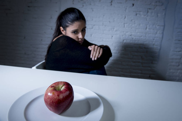 jonge vrouw of tiener op zoek van apple fruit op schotel als symbool van gekke dieet in voeding stoornis - Foto, afbeelding