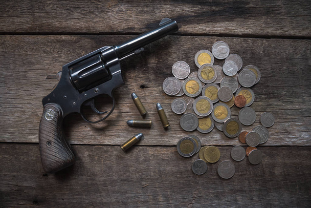 Gun and coins on wooden table. top view - Photo, Image