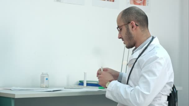 Male doctor shaking down thermometer and handing it to the patient - Video, Çekim