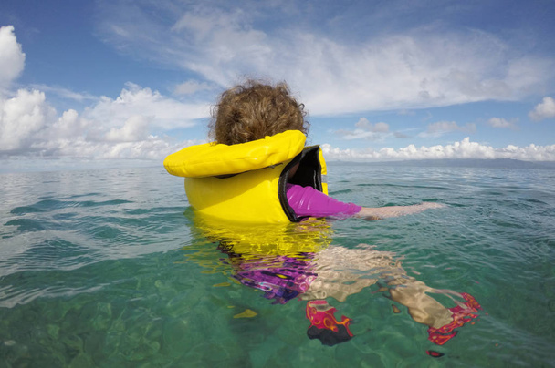 Bambino che galleggia con un giubbotto di salvataggio da solo nell'oceano
 - Foto, immagini