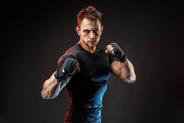 Studio portrait of fighting muscular man om dark background - Photo, image