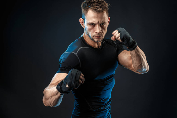 Studio portrait of fighting muscular man om dark background - Foto, Imagem