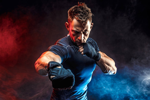 Studio portrait of fighting muscular man in smoke - Фото, зображення